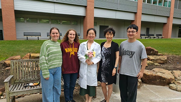 A group of people standing together, one in a white coat