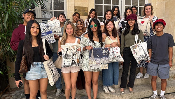 Large group of people standing in front of a building with "Rice University Global Paris Center" engraved onto a plaque