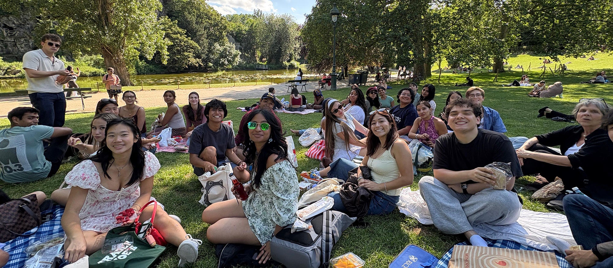 Several people sitting on picnic blankets in a park
