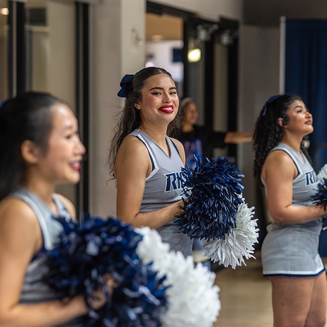 Three cheerleaders, with one facing the camera