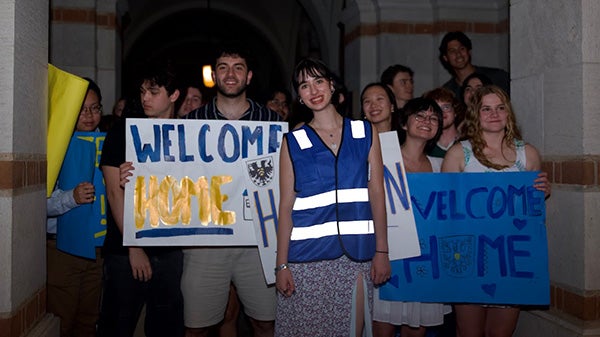 Nighttime photo of people holding signs behind a girl in a blue traffic vest