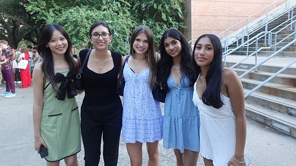 Five girls in dresses standing together, smiling at the camera