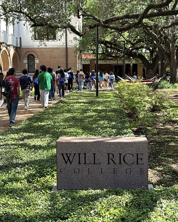 Plaque sitting in a grassy strip of land that says "Will Rice College"