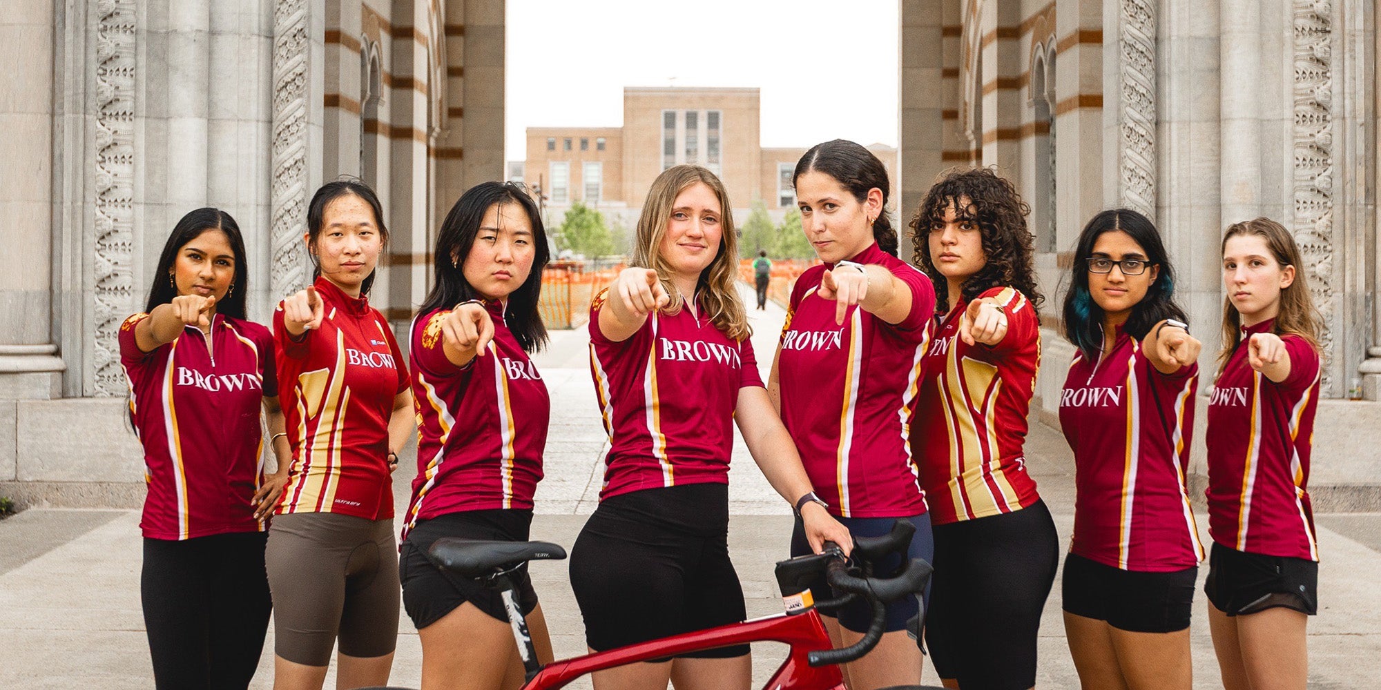 Girls in matching red shirts and black shorts, pointing at camera menacingly