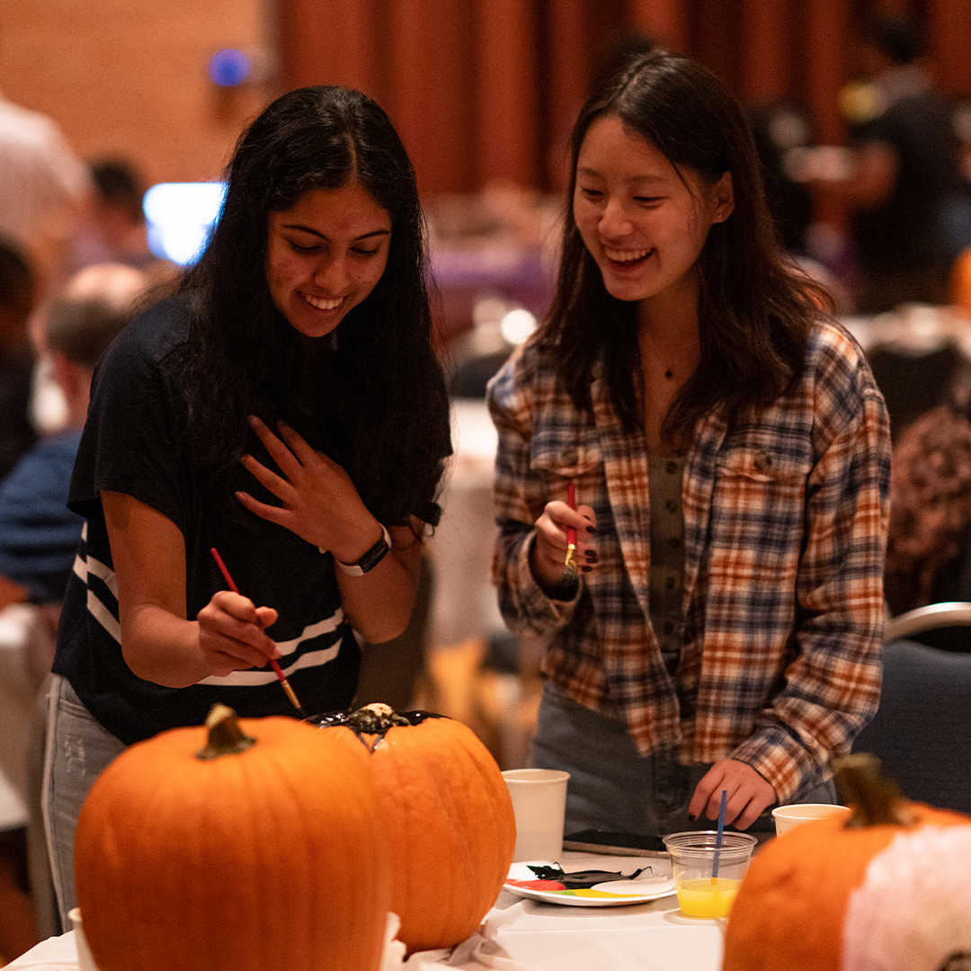 Two Rice students paint a pumpkin together for Halloween