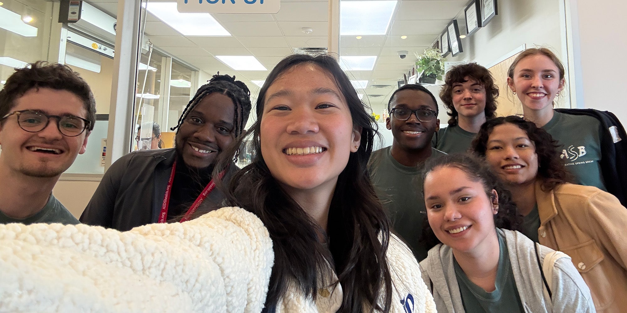 Selfie of several students in front of clear glass window 