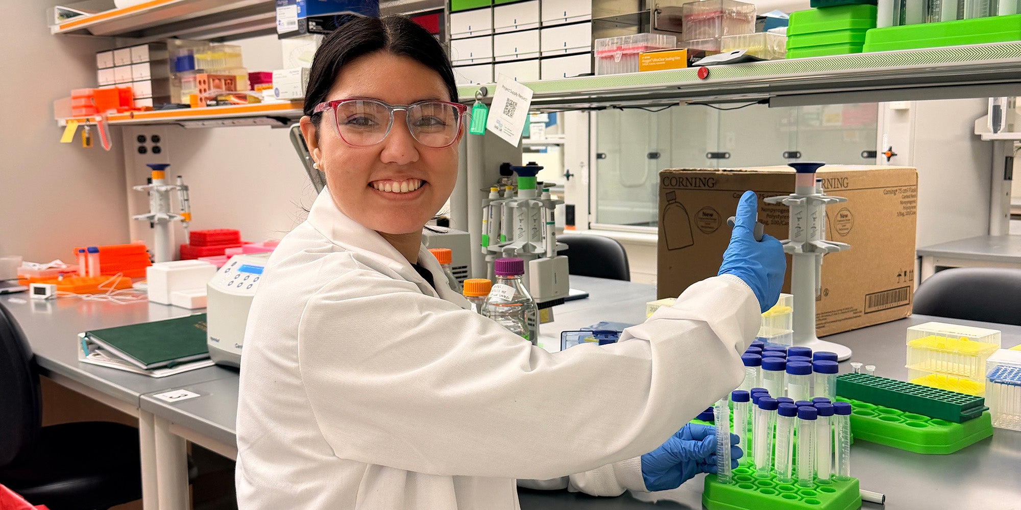 A girl working in a science lab, turned to smile at the camera