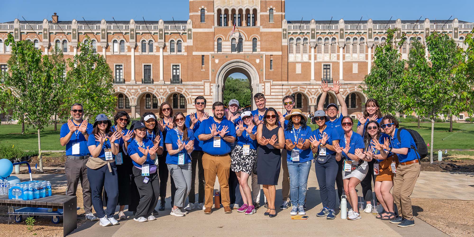 Large group photo of people in matching blue shirts in front of a building
