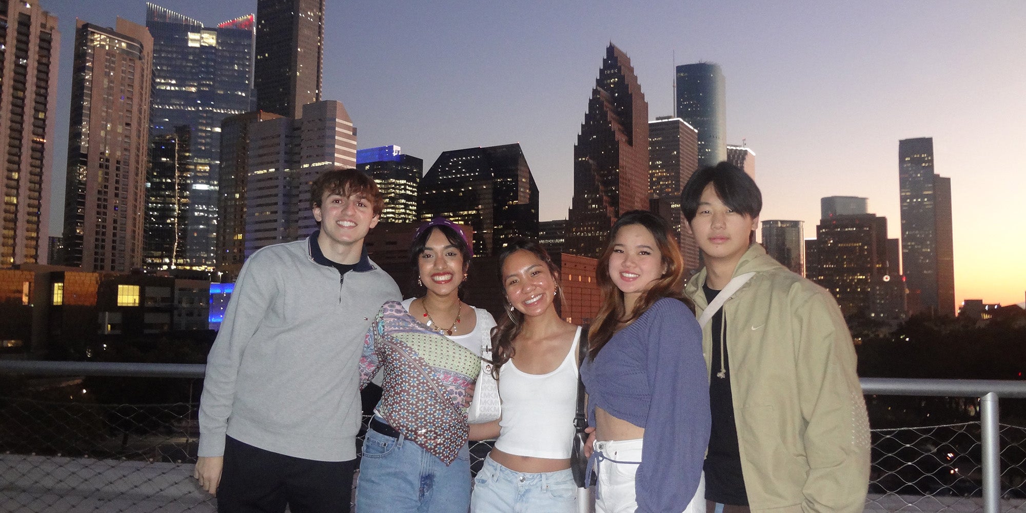 Five people standing in front of a skyline at dusk