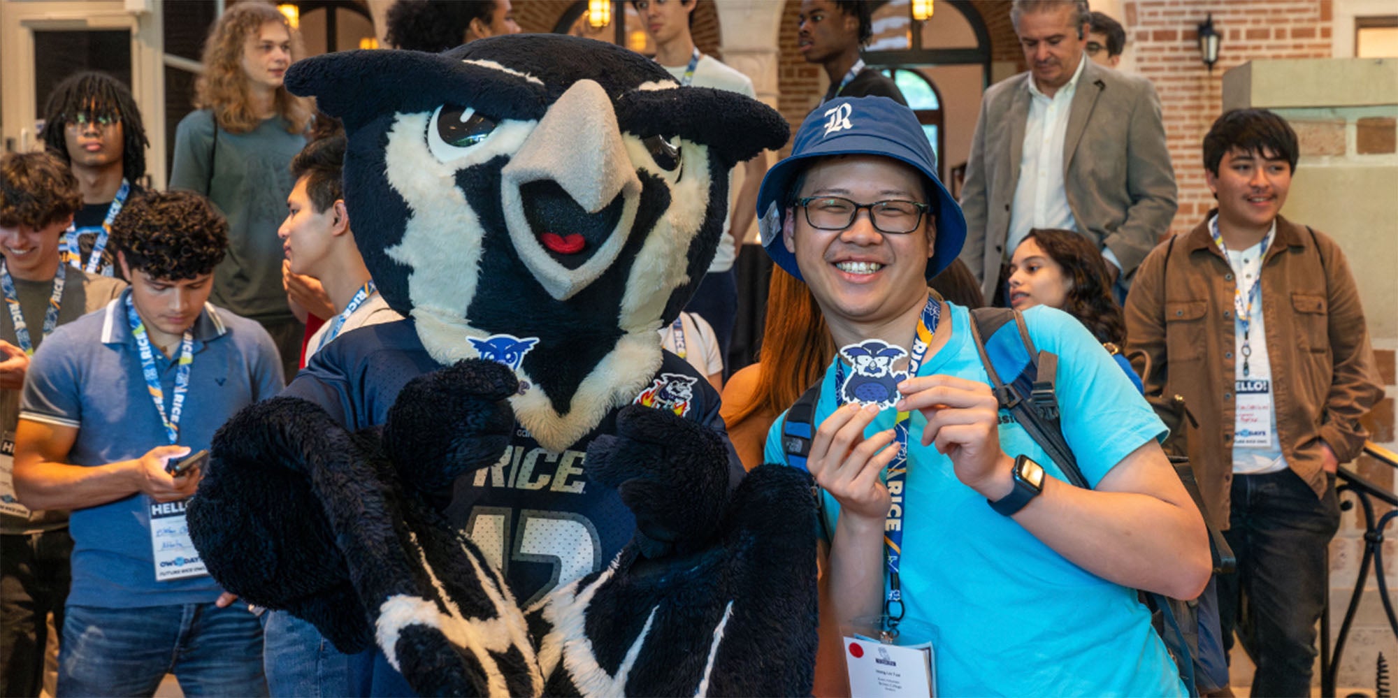 A Rice student posing with the Rice Owl mascot Sammy
