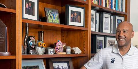 A photo of Provost Reginald DesRoches smiling as he leans against a bookshelf inside his office.