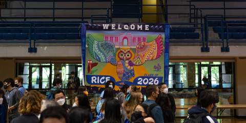 This picture is taken inside Rice's main basketball court, with the focus being the large multicolor Owl mural that hangs from the second floor and says Welcome Rice Class of 2026.