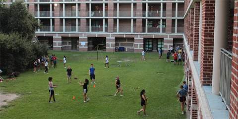 Students playing football and socializing in a grassy area.
