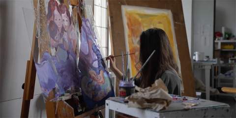 Female student painting on a canvas.
