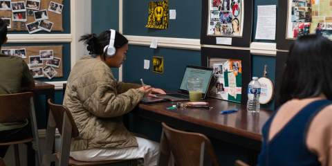 Student sitting in coffeehouse on their laptop 