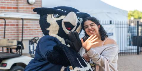Admitted student making a Rice Owls handsign with Sammy the Owl.