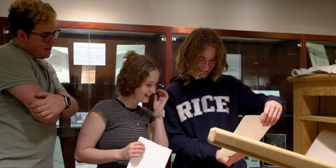 Students looking at the prints they created with the Blake press replica.