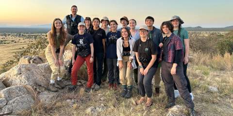 A group of college students squatting and posing in the African Savannah