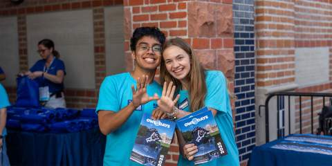 Two students holding up their Rice Owls hand signs.