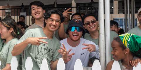 Male college students in spirit wear T-shirts making peace signs at the camera