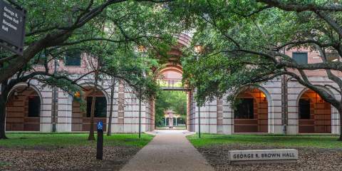 The tree-covered entrance to George R. Brown Hall on the Rice campus