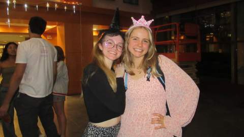 Two girls posing for a photo in black and pink colored outfits