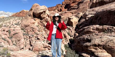Girl standing in large rocky environment, putting up thumbs ups