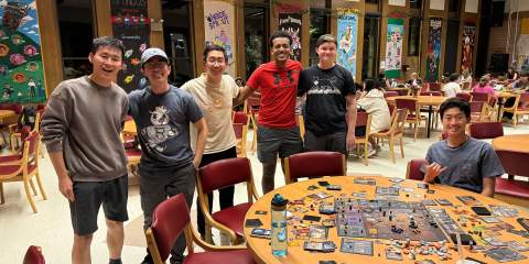 Boys standing behind a round table with cards on it