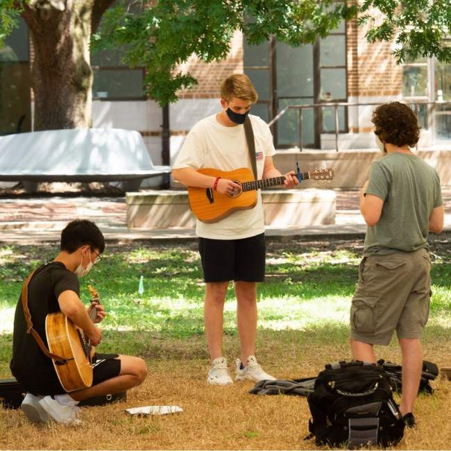 Students playing guitar outside