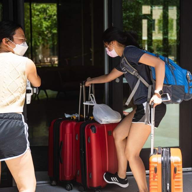 A female student brings her luggage inside her new dorm