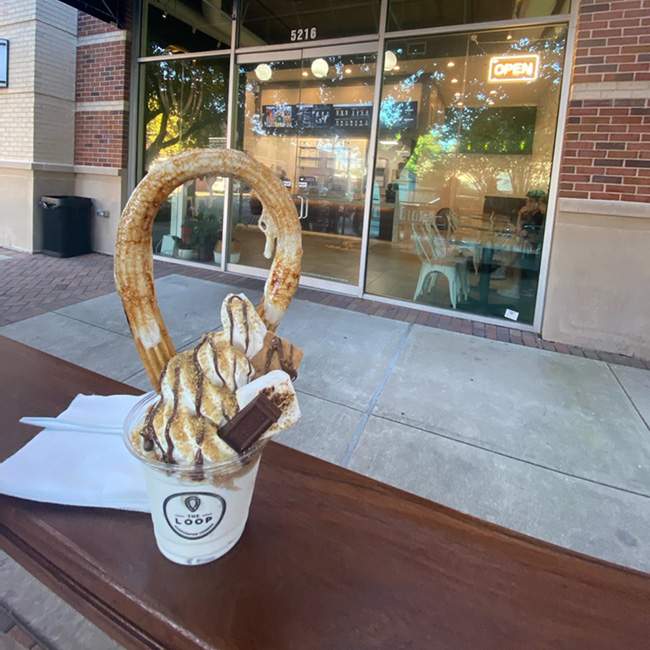 A picture of a churro in the shape of a loop stuck in a cup of soft serve ice cream.