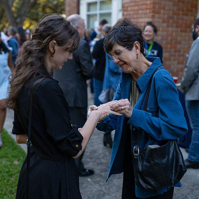 A mom of a female Rice student puts a Rice class ring on her daughter's finger.