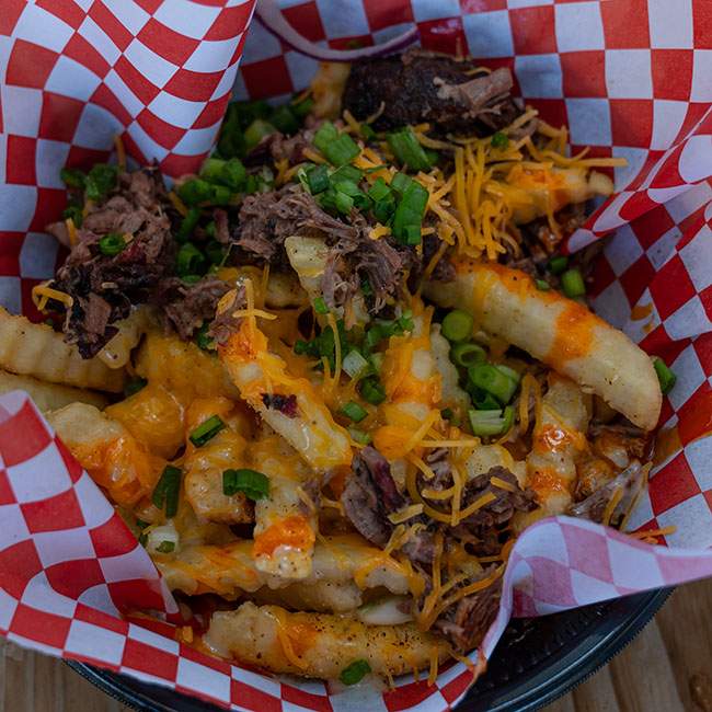 A picture of a basket of fries with cheese and brisket on top.