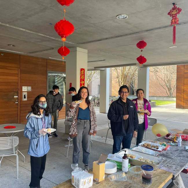 A group of students standing in front of a table with food for a Chinese New Year celebration.
