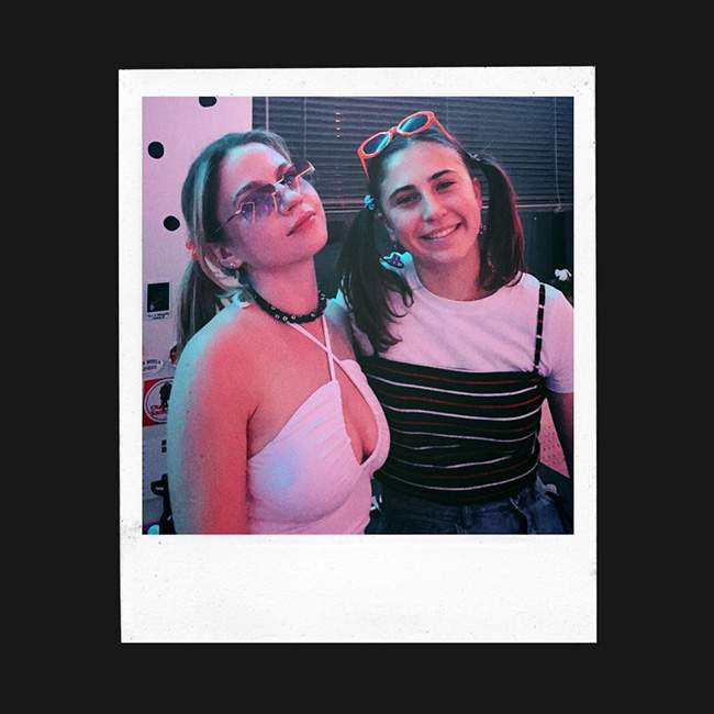 Two female Rice students pose for a picture from the Y2K party, and the picture is edited to look like a polaroid.