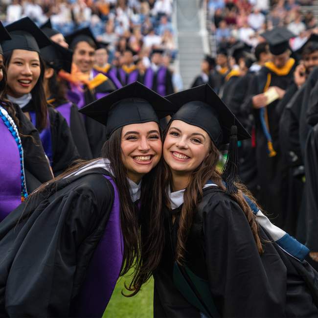 Rice grads pose as they walk through Rice University's stadium for graduation