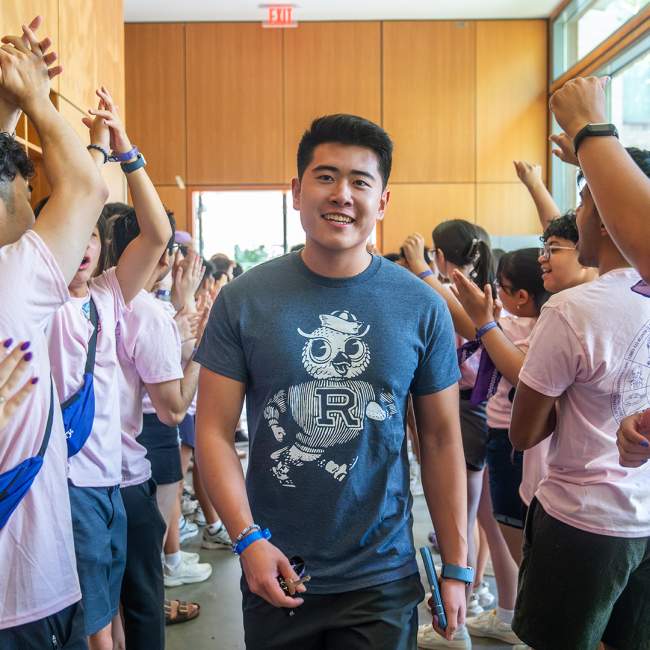 New student walking down between a crowd of people cheering for him