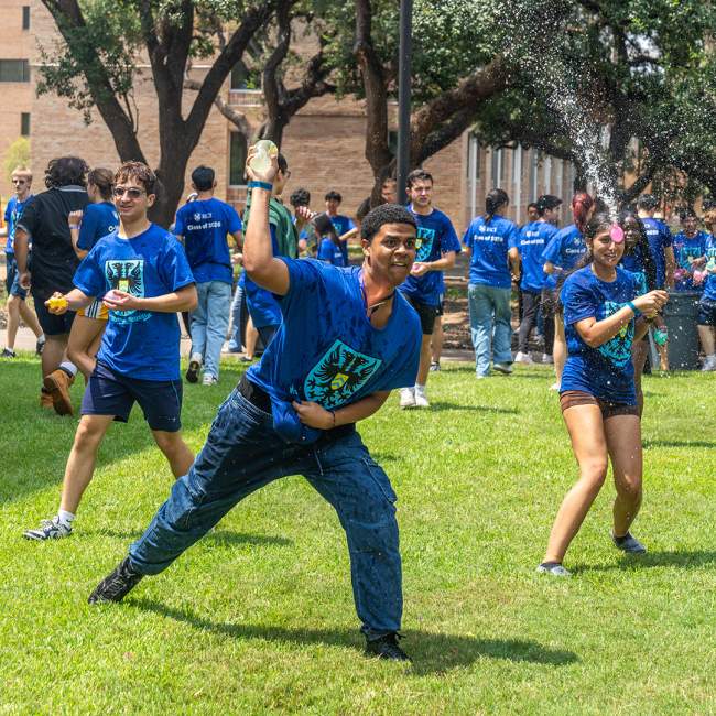 A student is throwing a water balloon while others in the background take aim