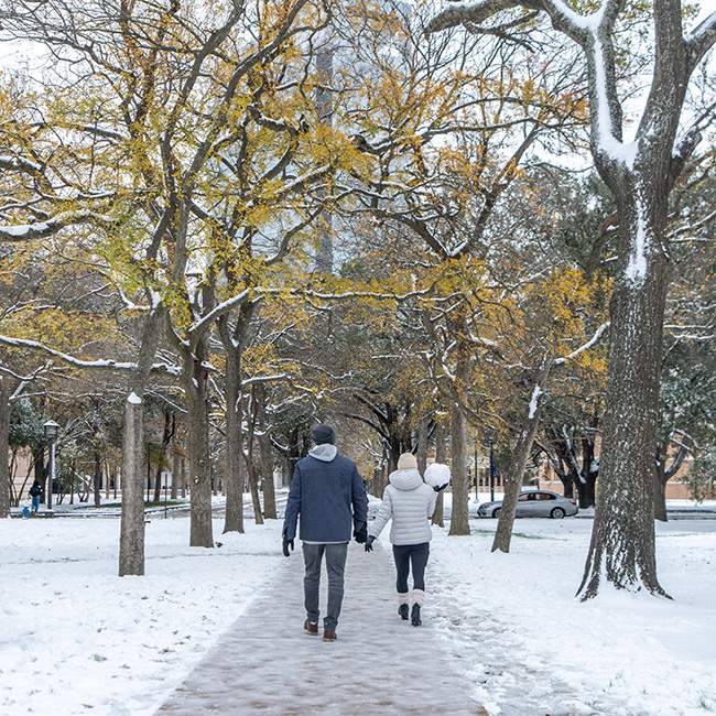 Two people walking down a snowy walkway