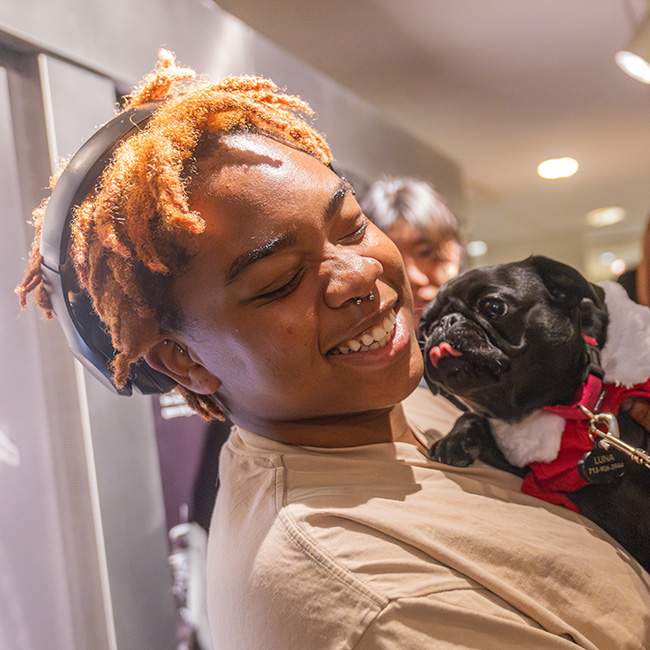 A female college student holding a black pug 