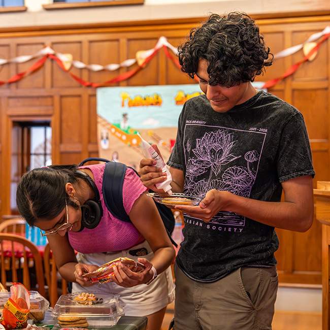 Two students crouched down, painting cookies