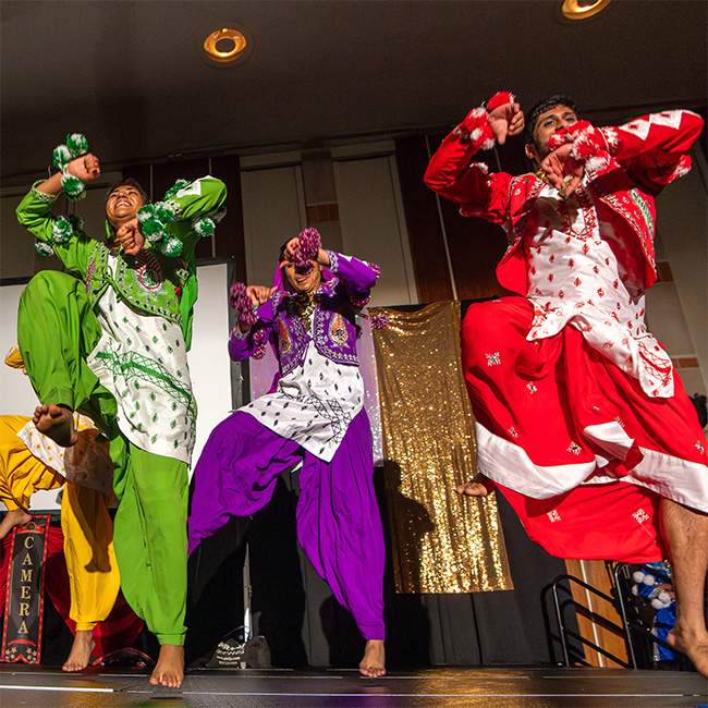 Three dancers in vividly colored Indian outfits