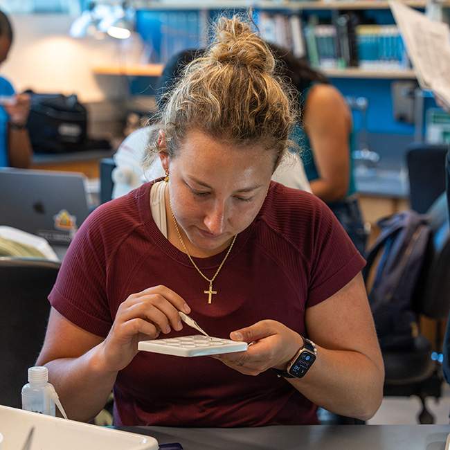 A girl using tweezers on a plate with small compartments