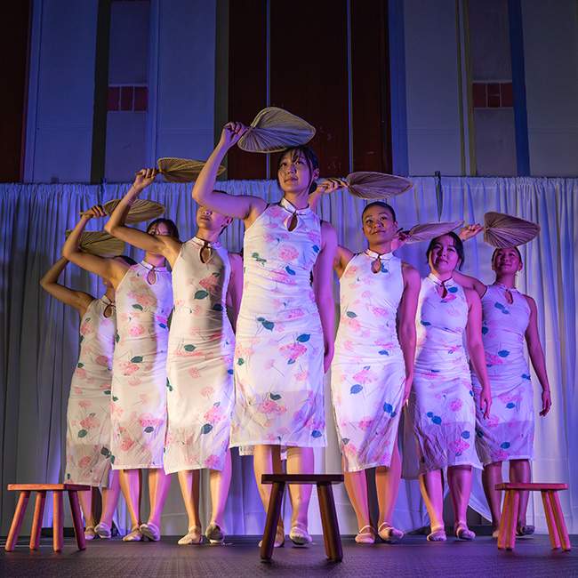 Girls in matching dresses making matching poses with matching props on a stage