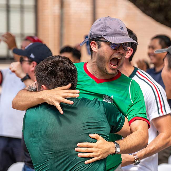 Two people excitedly hugging, one with back turned to the camera, the other mid-scream