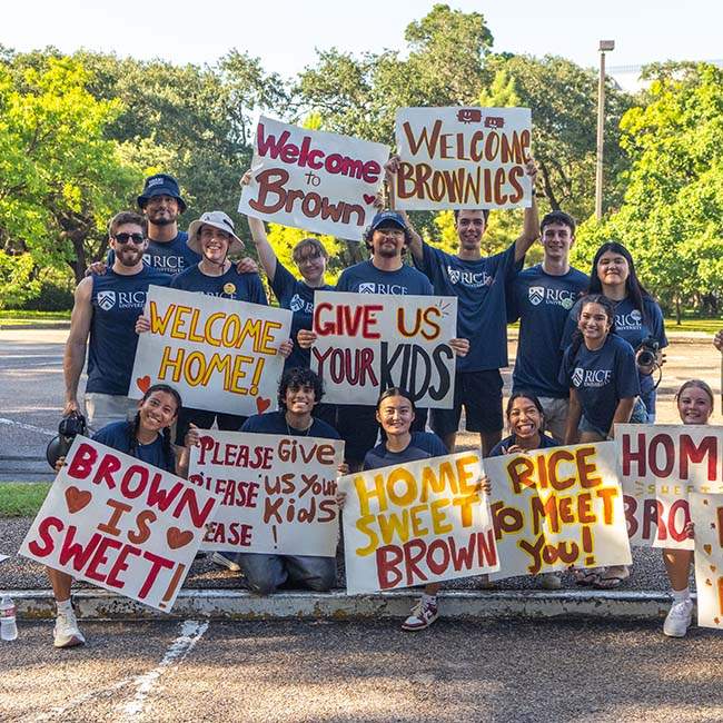 Group of people in matching blue shirts, holding up posters with large cheering messages