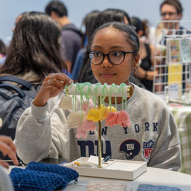 A girl showing a small rack with crochet flowers dangling off