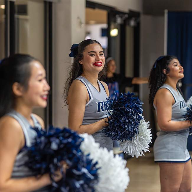 Three cheerleaders, with one facing the camera